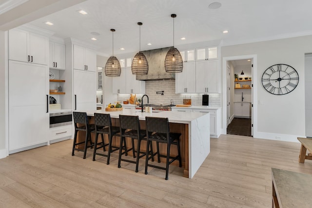 7025 Lanceleaf Dr, College Grove, TN 37046 - kitchen with light wood-style flooring, backsplash, a large island with sink, and recessed lighting