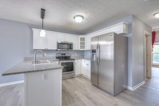 5766 Amalie Dr, Nashville, TN 37211 - kitchen with stainless steel appliances, a peninsula, light wood finished floors, light stone countertops, and a textured ceiling