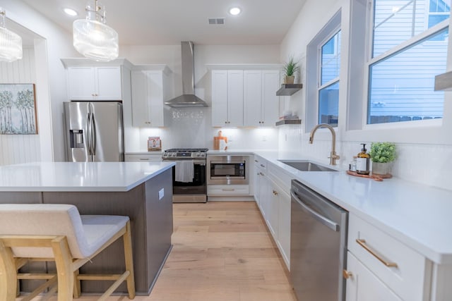 4076 Penfield Dr Unit A, Franklin, TN 37069 - kitchen with stainless steel appliances, wall chimney range hood, a kitchen breakfast bar, white cabinets, and light wood-type flooring
