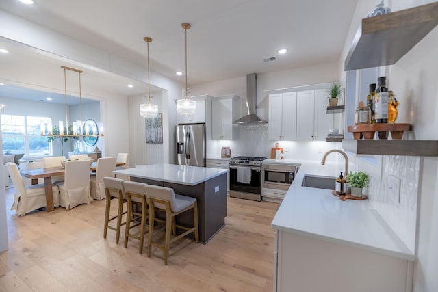 4068 Penfield Dr Unit C, Franklin, TN 37069 - kitchen with appliances with stainless steel finishes, wall chimney exhaust hood, a center island, a breakfast bar, and light wood finished floors
