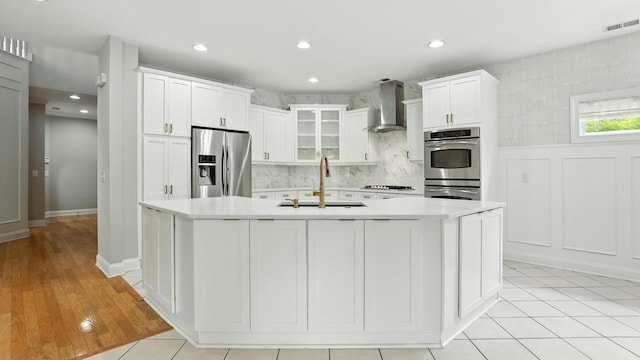 2976 Kingston Cir S, Mount Juliet, TN 37122 - kitchen with appliances with stainless steel finishes, wall chimney exhaust hood, light countertops, white cabinetry, and a kitchen island with sink