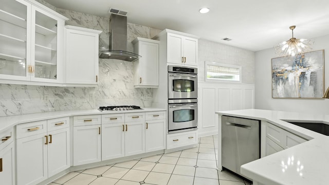 2976 Kingston Cir S, Mount Juliet, TN 37122 - kitchen featuring wall chimney range hood, stainless steel appliances, a chandelier, tasteful backsplash, and light countertops