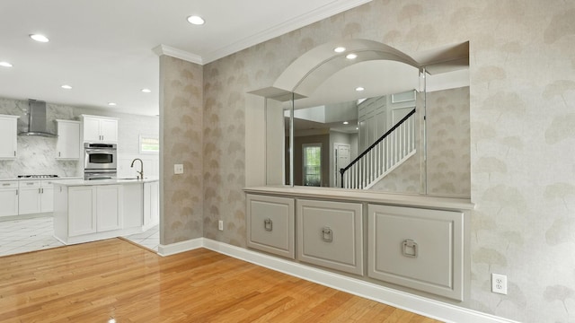 2976 Kingston Cir S, Mount Juliet, TN 37122 - kitchen featuring wall chimney exhaust hood, stovetop, light wood-type flooring, ornamental molding, and healthy amount of natural light