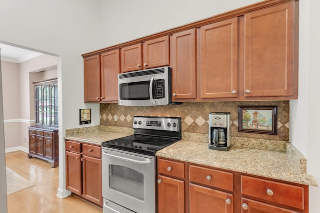 5019 John Hagar Rd, Hermitage, TN 37076 - kitchen with appliances with stainless steel finishes, ornamental molding, backsplash, light wood finished floors, and light stone countertops