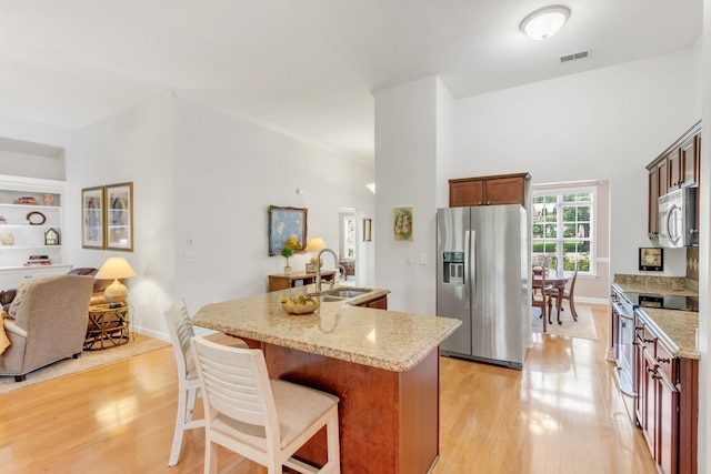 5019 John Hagar Rd, Hermitage, TN 37076 - kitchen featuring appliances with stainless steel finishes, light wood-style floors, light stone counters, and a kitchen breakfast bar