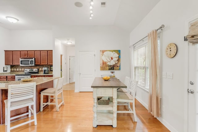 5019 John Hagar Rd, Hermitage, TN 37076 - kitchen featuring appliances with stainless steel finishes, a breakfast bar area, tasteful backsplash, light wood-style floors, and light stone counters