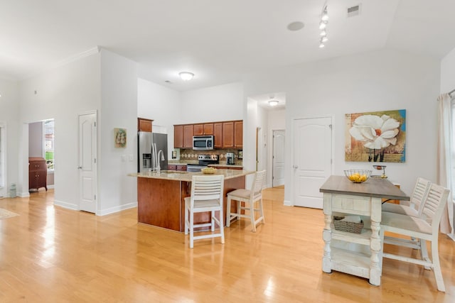 5019 John Hagar Rd, Hermitage, TN 37076 - kitchen featuring stainless steel appliances, a kitchen bar, light wood finished floors, and high vaulted ceiling