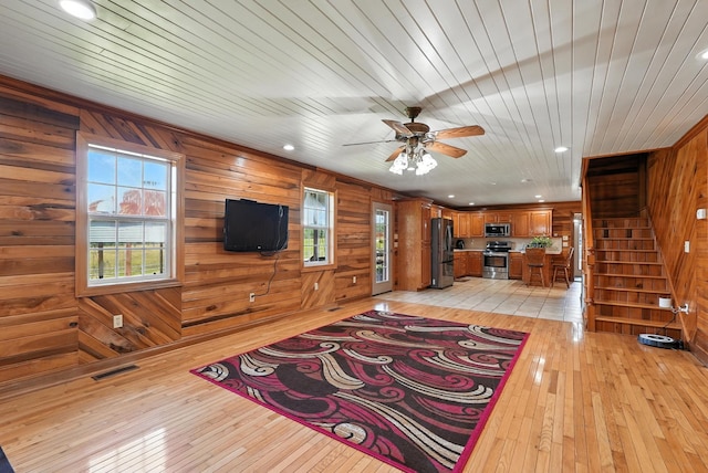 1880 Clydeton Rd, Waverly, TN 37185 - unfurnished living room with light wood-type flooring, wood walls, stairs, ceiling fan, and wooden ceiling