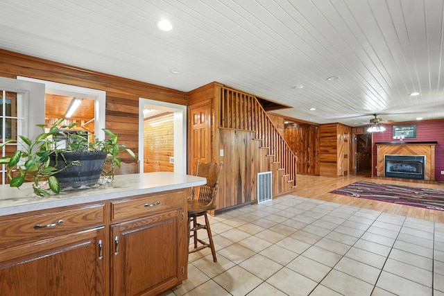 1880 Clydeton Rd, Waverly, TN 37185 - kitchen featuring wood walls, light tile patterned floors, light countertops, a fireplace, and a ceiling fan
