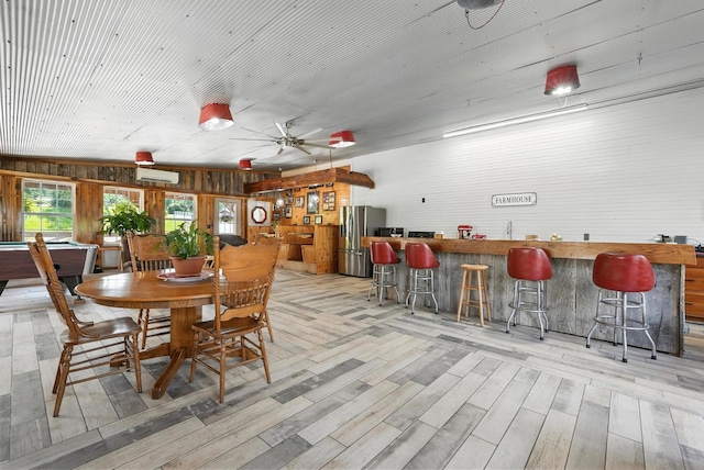 1880 Clydeton Rd, Waverly, TN 37185 - dining area featuring a bar, a wall mounted AC, light wood-style flooring, a ceiling fan, and wooden walls