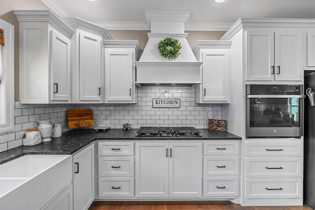 268 Planters Cir, Leoma, TN 38468 - kitchen with stainless steel appliances, white cabinets, custom range hood, dark stone counters, and ornamental molding