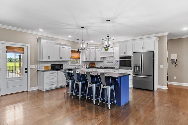 268 Planters Cir, Leoma, TN 38468 - kitchen featuring appliances with stainless steel finishes, dark countertops, a kitchen bar, backsplash, and dark wood-type flooring