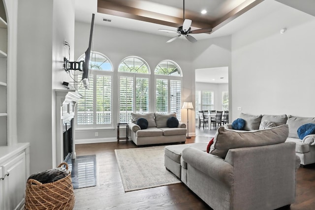 1069 Pleasant Valley Rd, Greenbrier, TN 37073 - living room featuring a tray ceiling, ceiling fan, dark wood-type flooring, a high ceiling, and a fireplace with flush hearth