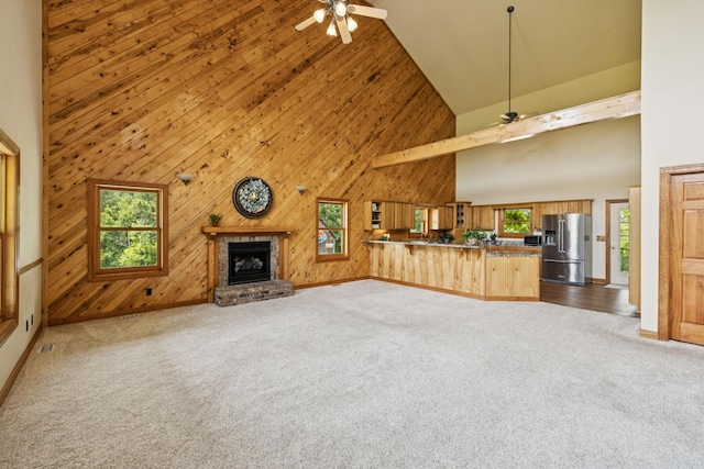 4255 Mcfall Rd, Cumberland City, TN 37050 - unfurnished living room featuring a ceiling fan, high vaulted ceiling, plenty of natural light, carpet, and wooden walls