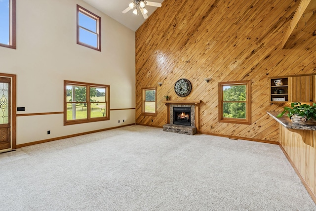 4255 Mcfall Rd, Cumberland City, TN 37050 - unfurnished living room with a towering ceiling, light colored carpet, a fireplace, wood walls, and a ceiling fan