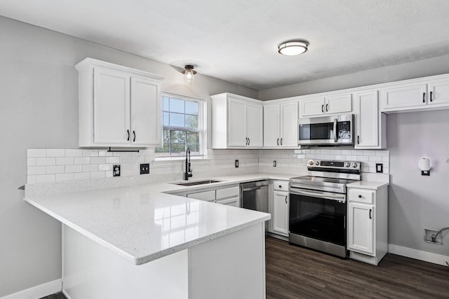 180 Bill Stewart Blvd, La Vergne, TN 37086 - kitchen featuring appliances with stainless steel finishes, a peninsula, white cabinets, decorative backsplash, and dark wood-style floors