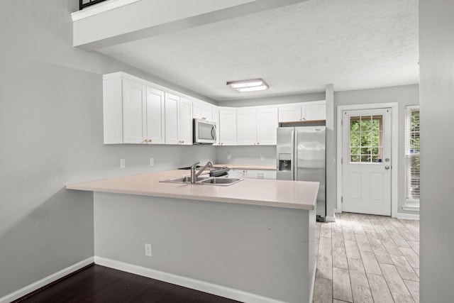 1029 Rachels Square Dr, Hermitage, TN 37076 - kitchen with appliances with stainless steel finishes, light wood finished floors, light countertops, a peninsula, and white cabinetry