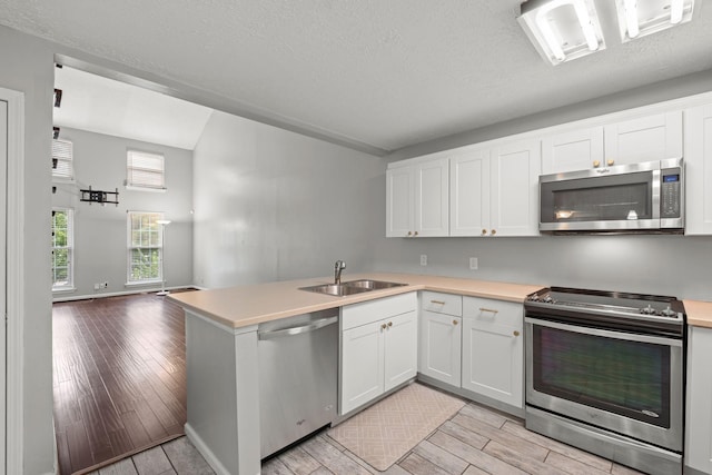1029 Rachels Square Dr, Hermitage, TN 37076 - kitchen featuring stainless steel appliances, wood finish floors, light countertops, a peninsula, and a textured ceiling