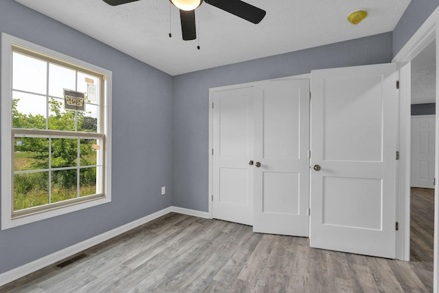 128 N C St, Hillsboro, TN 37342 - unfurnished bedroom featuring multiple windows, wood finished floors, a closet, a textured ceiling, and ceiling fan