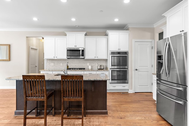 2213 Kirkwall Dr, Nolensville, TN 37135 - kitchen featuring appliances with stainless steel finishes, ornamental molding, decorative backsplash, a center island with sink, and white cabinets