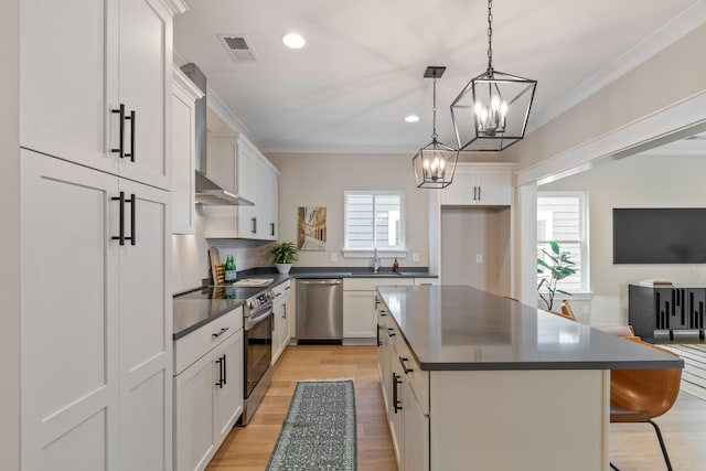 317 Delta Way, La Vergne, TN 37086 - kitchen featuring appliances with stainless steel finishes, dark countertops, wall chimney range hood, a chandelier, and light wood-style flooring