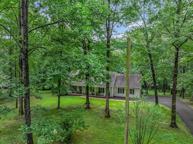 1064 Crane Ct, Kingston Springs, TN 37082 - view of front of home featuring asphalt driveway, covered porch, a front lawn, and a forest view