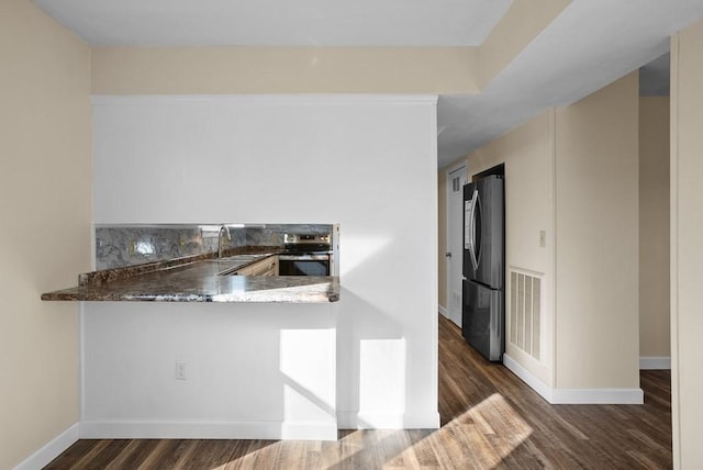 120 Dove Ln, Monroe, TN 38573 - kitchen featuring appliances with stainless steel finishes, decorative backsplash, wood finished floors, a peninsula, and dark stone countertops