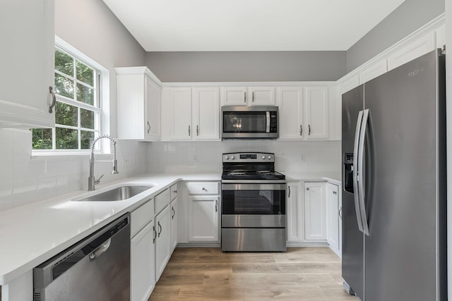 1220 Kelly Ct, Franklin, TN 37064 - kitchen featuring appliances with stainless steel finishes, white cabinets, light wood-type flooring, and tasteful backsplash