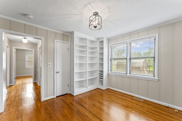 2709 Emery Dr, Nashville, TN 37214 - unfurnished dining area with wood finished floors, ornamental molding, built in shelves, a decorative wall, and a textured ceiling