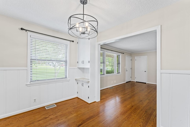 2709 Emery Dr, Nashville, TN 37214 - unfurnished dining area featuring a textured ceiling, a chandelier, wainscoting, wood finished floors, and a decorative wall