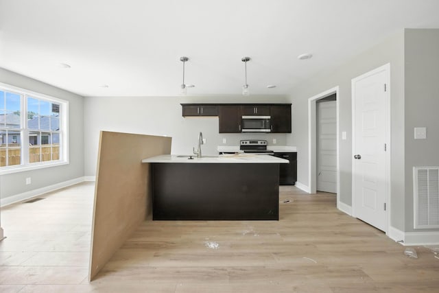 2670 Scott Dr, Clarksville, TN 37042 - kitchen with appliances with stainless steel finishes, light wood-style floors, light countertops, pendant lighting, and a kitchen island with sink