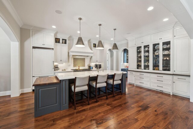 114 Middleton Cir, Nashville, TN 37215 - kitchen featuring custom range hood, white cabinetry, arched walkways, a spacious island, and ornamental molding
