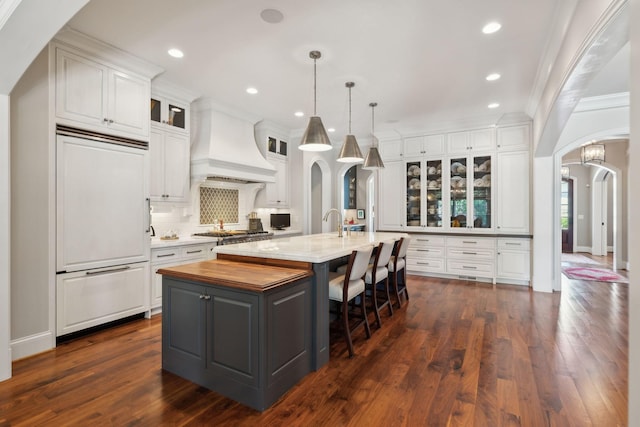 114 Middleton Cir, Nashville, TN 37215 - kitchen with paneled built in fridge, premium range hood, arched walkways, a center island with sink, and white cabinetry