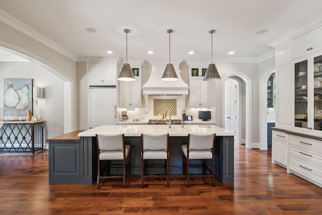 114 Middleton Cir, Nashville, TN 37215 - kitchen with arched walkways, custom exhaust hood, white cabinetry, a large island with sink, and crown molding