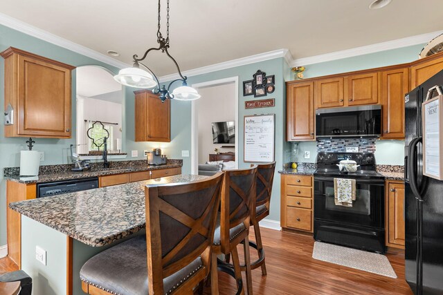 604 Applejack Ct, Antioch, TN 37013 - kitchen with black appliances, ornamental molding, a kitchen breakfast bar, wood finished floors, and a kitchen island