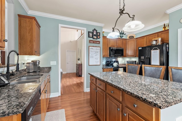 604 Applejack Ct, Antioch, TN 37013 - kitchen featuring black appliances, light wood-style flooring, crown molding, brown cabinets, and dark stone countertops