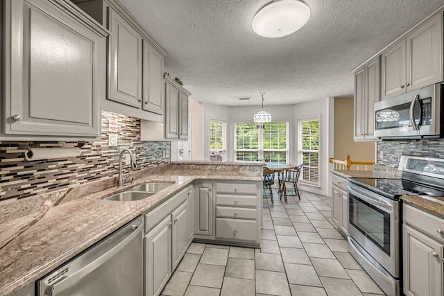 1013 Laurel Hills Dr, Dickson, TN 37055 - kitchen with stainless steel appliances, gray cabinetry, decorative backsplash, light tile patterned flooring, and a peninsula