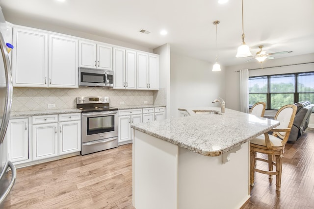 835 Meadowcrest Way, Lebanon, TN 37090 - kitchen featuring stainless steel appliances, light wood-style flooring, white cabinets, a breakfast bar area, and recessed lighting