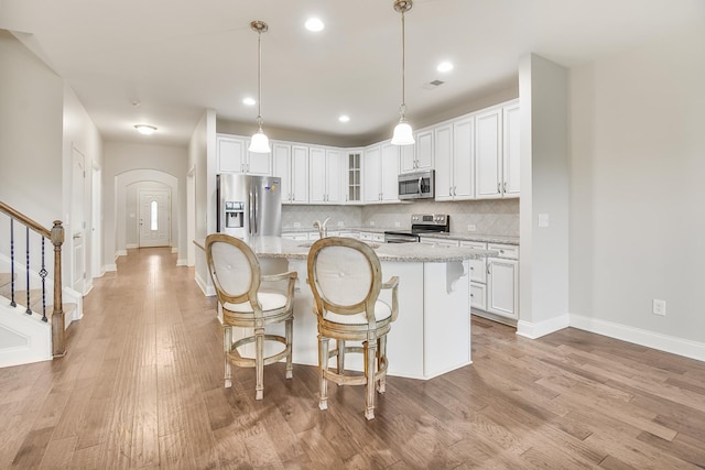 835 Meadowcrest Way, Lebanon, TN 37090 - kitchen with appliances with stainless steel finishes, arched walkways, white cabinets, decorative backsplash, and light wood-type flooring
