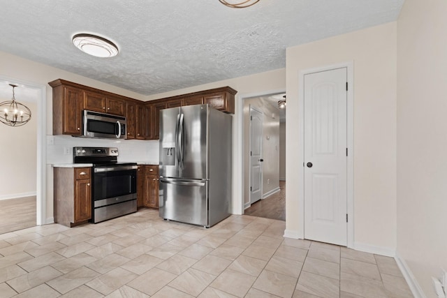 989 Ernest Stewart Dr, Clarksville, TN 37042 - kitchen featuring appliances with stainless steel finishes, light countertops, a chandelier, tasteful backsplash, and a textured ceiling