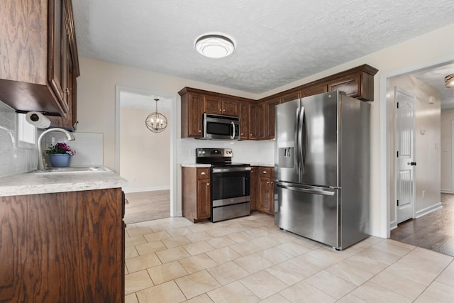989 Ernest Stewart Dr, Clarksville, TN 37042 - kitchen with appliances with stainless steel finishes, light countertops, backsplash, light tile patterned floors, and dark brown cabinetry