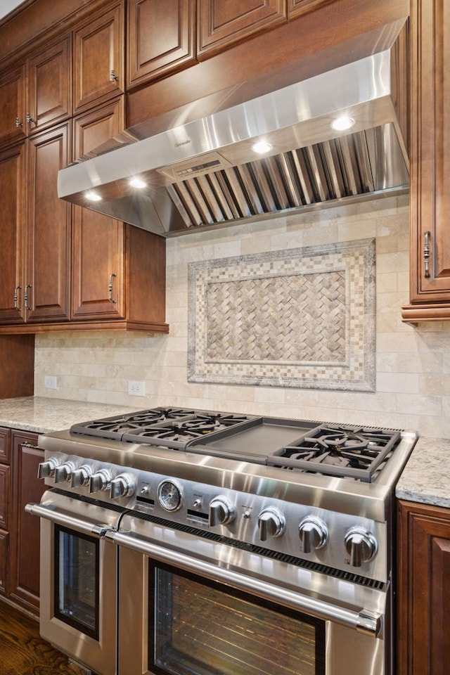 703 Welsh Ln, Franklin, TN 37064 - kitchen featuring double oven range, ventilation hood, tasteful backsplash, light stone counters, and brown cabinets