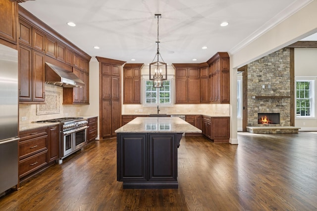703 Welsh Ln, Franklin, TN 37064 - kitchen with wall chimney range hood, high quality appliances, dark wood-style flooring, light stone counters, and a kitchen island