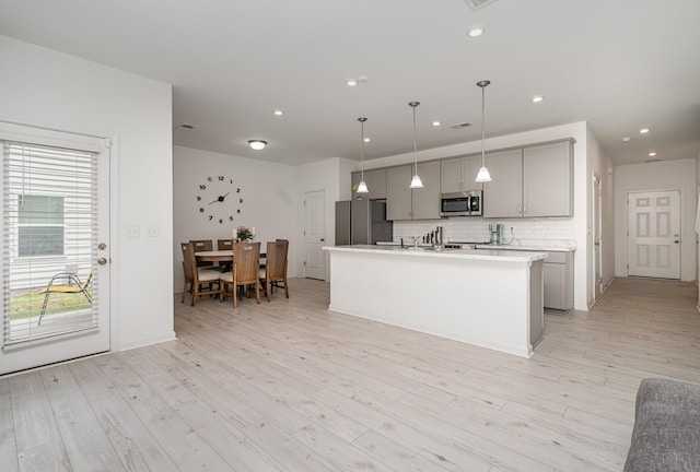 3716 Capstone Dr, Murfreesboro, TN 37128 - kitchen featuring appliances with stainless steel finishes, gray cabinets, tasteful backsplash, light countertops, and a kitchen island with sink