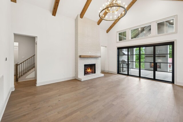 6628 Bethesda Arno Rd, Thompsons Station, TN 37179 - unfurnished living room featuring high vaulted ceiling, a chandelier, wood finished floors, beamed ceiling, and a brick fireplace