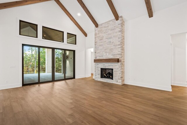 6628 Bethesda Arno Rd, Thompsons Station, TN 37179 - unfurnished living room with high vaulted ceiling, beamed ceiling, wood finished floors, and a stone fireplace