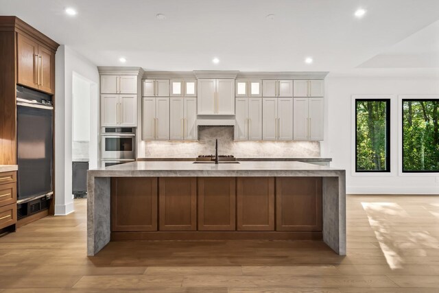 6628 Bethesda Arno Rd, Thompsons Station, TN 37179 - kitchen with decorative backsplash, recessed lighting, a large island with sink, light wood-style flooring, and light countertops