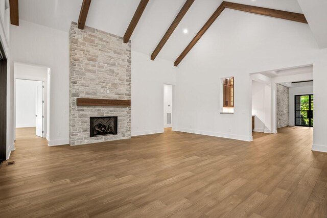 6628 Bethesda Arno Rd, Thompsons Station, TN 37179 - unfurnished living room with high vaulted ceiling, beam ceiling, a stone fireplace, and wood finished floors