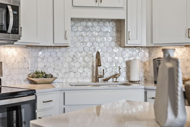 2101 Branford Pl Unit 201, Thompsons Station, TN 37179 - kitchen with stainless steel appliances, decorative backsplash, white cabinets, and light stone countertops