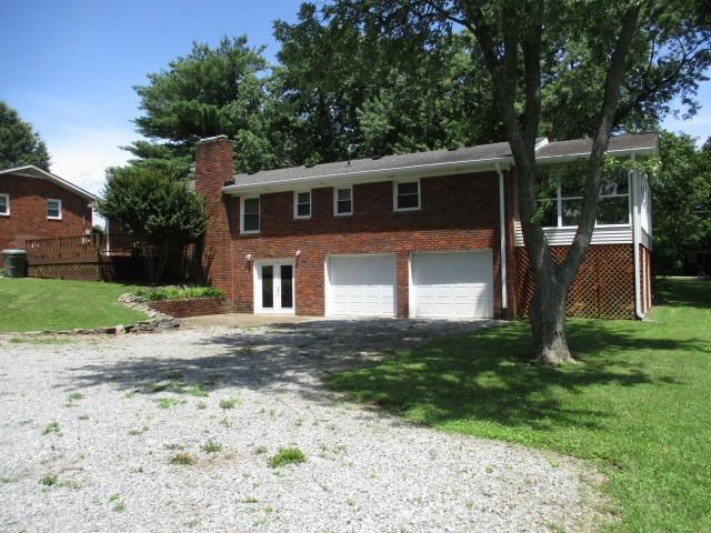 829 Kenny St, Gallatin, TN 37066 - view of front facade with an attached garage, a chimney, driveway, brick siding, and a front lawn